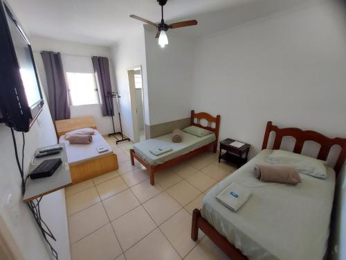 uma sala de estar com 2 camas e uma televisão de ecrã plano em Quartos com Banheiros privativos - Hospedagem Recanto do Luar em Taubaté