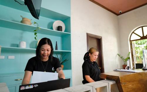 two women standing in a room with a laptop at Mad Monkey Dumaguete in Dumaguete