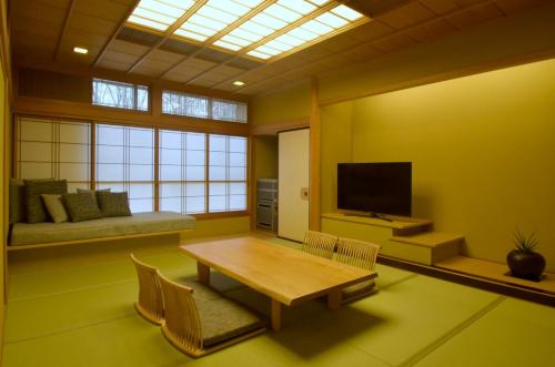 a living room with a table and a television at Suizantei Club Jozankei-Adults Only in Jozankei