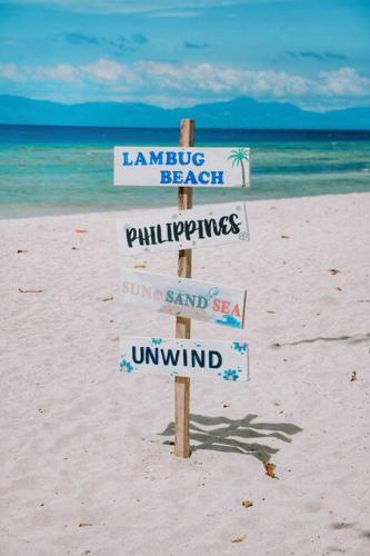 a sign on a beach with signs on the sand at The Verge Cebu Beachfront King Bed Pool Villa - 12 Minutes to Kawasan Falls Canyoneering in Badian