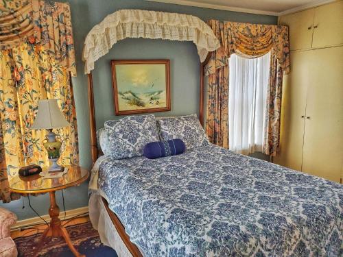 Schlafzimmer mit einem Bett mit blauer Decke in der Unterkunft Montague Inn Bed & Breakfast in Saginaw