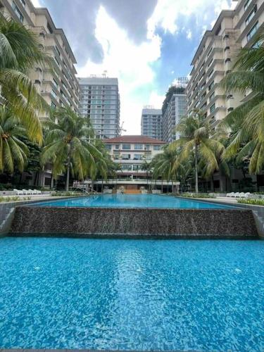 a large swimming pool with palm trees and buildings at Cozy 1 Bedroom Condo w Balcony in Shah Alam