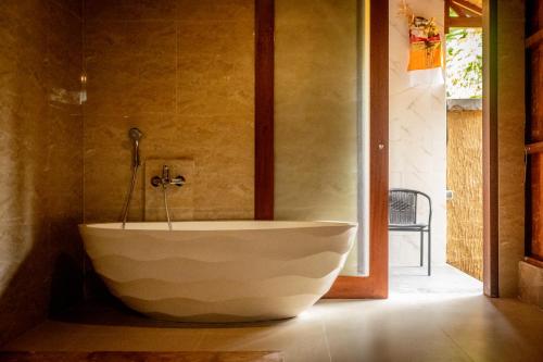 ein Bad mit einer großen weißen Badewanne in einem Zimmer in der Unterkunft Toya Sutra Villa in Tampaksiring