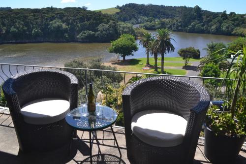 a balcony with two chairs and a table with a view of a river at Waterfalls Estate - Motel & Campground in Paihia
