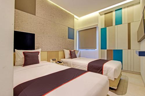 Habitación de hotel con 2 camas y ventana en Townhouse Oak IXO Hotel en Semarang