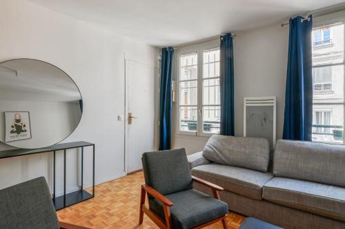 un salon avec un canapé et un miroir dans l'établissement Appartement Garnet - Welkeys, à Paris