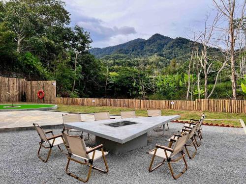 a picnic table and chairs with mountains in the background at The White Box (Genting Highland Foot Area) in Bentong