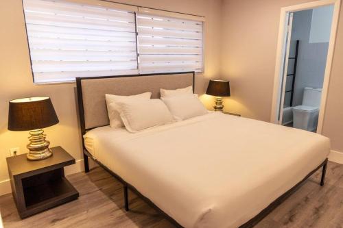 1 dormitorio con 1 cama blanca grande y 2 lámparas en Zoka House 5 mints from Brickell, en Miami