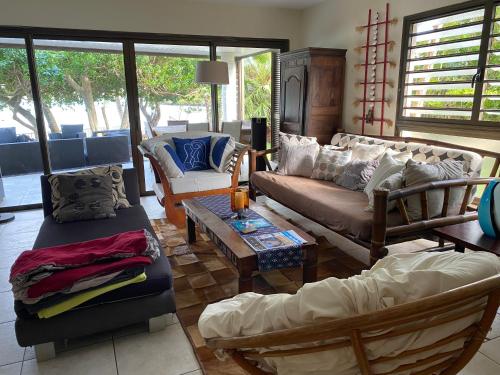 uma sala de estar com um sofá, cadeiras e uma mesa em Michelle’s flat by the Sea em Noumea