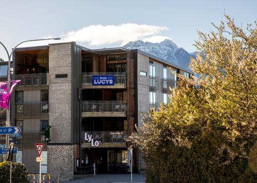 a building with a sign on it with mountains in the background at LyLo Queenstown in Queenstown