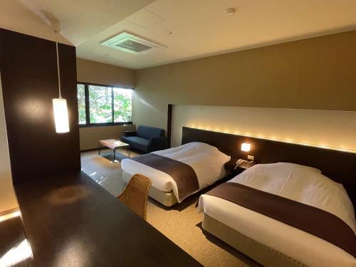 a hotel room with two beds and a chair at Ame no Hi to Yuyake-Adult Only in Chitose