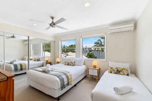 Dos camas en una habitación con dos ventanas. en Noosa Entrance Waterfront Resort, en Noosaville