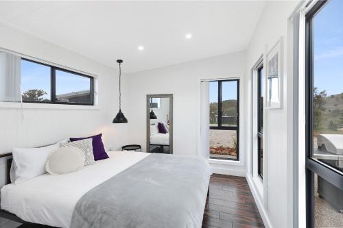 a bedroom with a large white bed and windows at Amethyst - 1 Bed with Hot Tub - Kundalini Lodge in Grattai