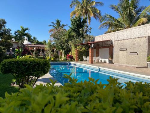 a swimming pool in front of a house with palm trees at Quinta Doña Carlota in Chiconcuac