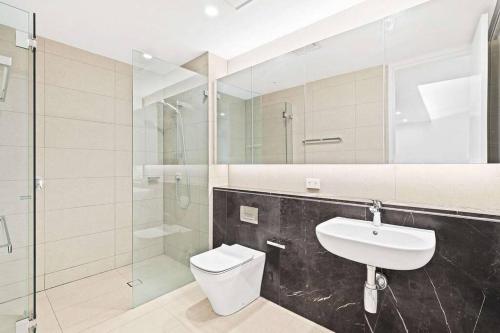 a bathroom with a toilet and a sink and a shower at One Bedroom with Roof Top Pool in Sydney