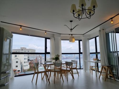 comedor con mesa, sillas y ventanas grandes en Mirage Yeondo Ocean view Rooftop, en Busan