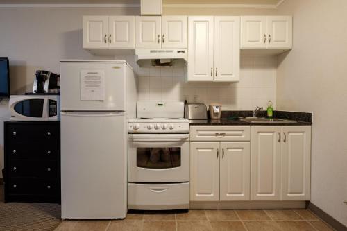 Perfect Inns & Suites في Weyburn: مطبخ مع أجهزة بيضاء ودواليب بيضاء