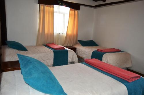a room with three beds with blue pillows on them at Samay Kirutoa Lodge in Quilotoa