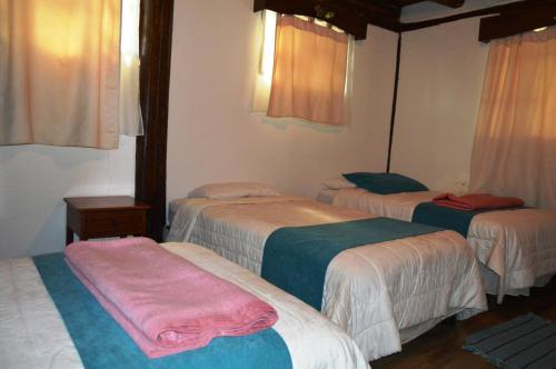 a hotel room with three beds in a room at Samay Kirutoa Lodge in Quilotoa