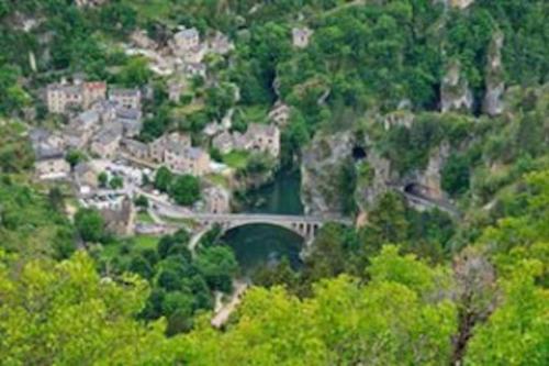 un puente sobre un río en un pueblo con árboles en Au Bon vivre chez gégé 13 quartier de la Bessède, en Florac