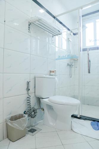 a white bathroom with a toilet and a shower at Hotel Totara in Dar es Salaam