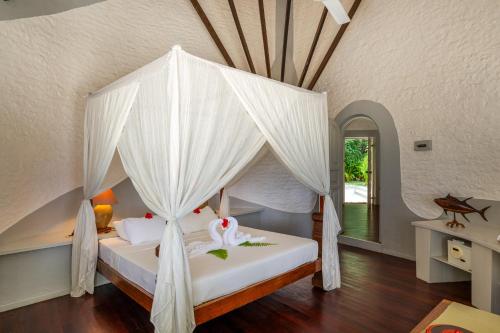 a bedroom with a bed with a canopy at Nika Island Resort & Spa, Maldives in Nika Island