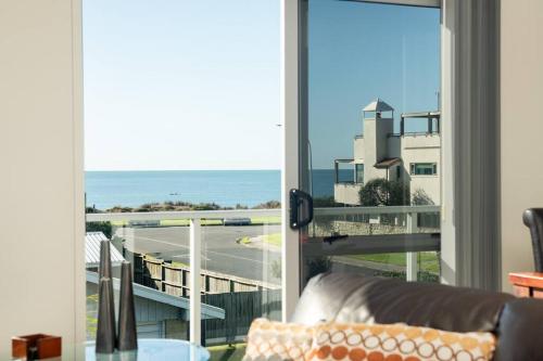 a living room with a couch and a view of the ocean at Longbeach Ocean Paradise in Mount Maunganui