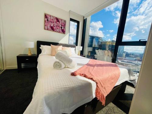 een slaapkamer met een wit bed en een groot raam bij Entire Unit in Front of Crown w/Free Parking in Melbourne