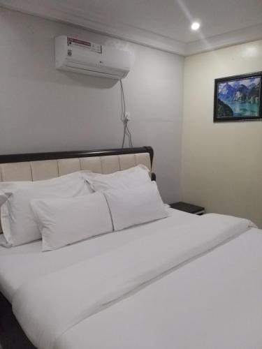 1 cama blanca con almohadas blancas y aire acondicionado en MITOS LUXURY SUITES -Somosu, en Lagos