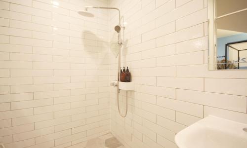 a white tiled bathroom with a shower and a sink at Iksan 4 Seasons Hotel in Iksan