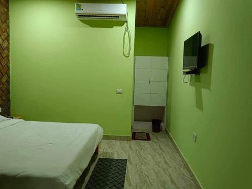 a green room with a bed and a television and a room with at Shri Jai Krishna Homestay in Rāmnagar