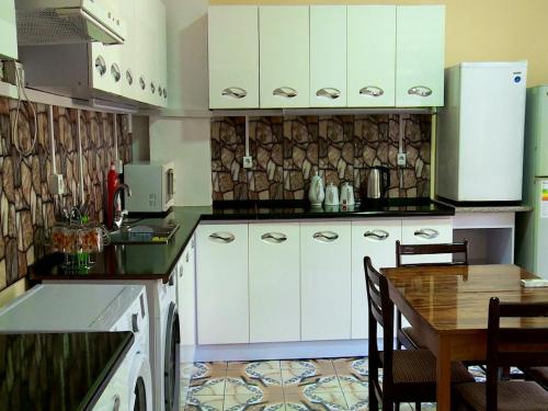 a kitchen with white cabinets and a wooden table at OROM Hostel in Dushanbe