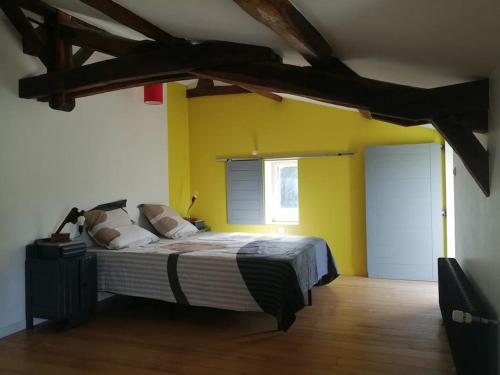 - une chambre avec un lit et un mur jaune dans l'établissement maison pleine de charme, à Saint-Étienne-de-Mer-Morte
