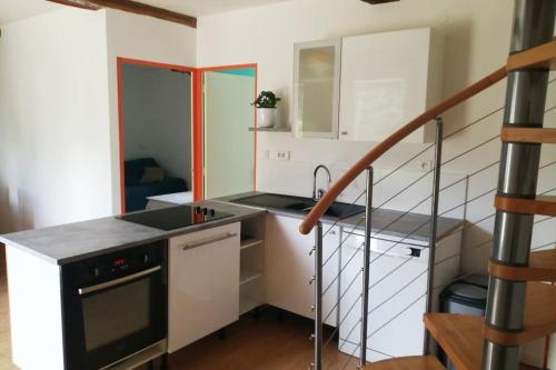 Una cocina con gabinetes blancos y una escalera. en maison pleine de charme, en Saint-Étienne-de-Mer-Morte
