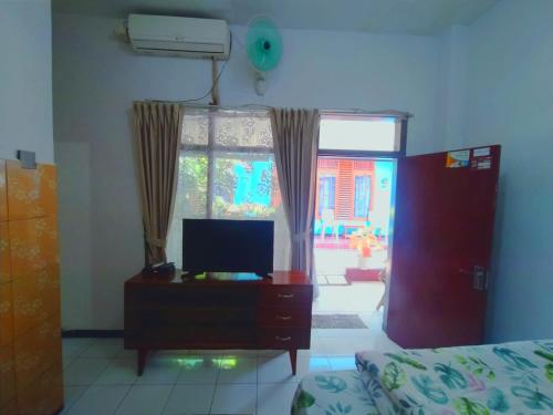 a living room with a tv on a dresser and a window at Aloha Living in Pangandaran