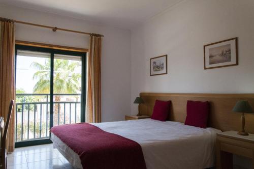a bedroom with a large bed and a balcony at Plaza Real by Atlantichotels in Portimão