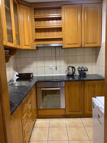 a kitchen with wooden cabinets and a black counter top at Stan na dan - Apartmani Q in Doboj