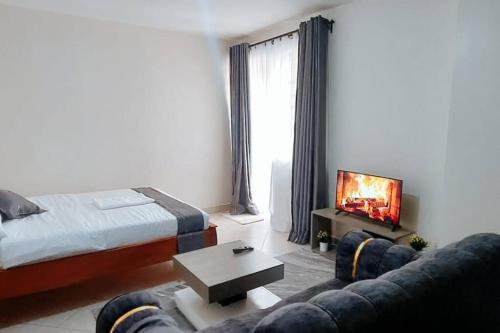 a bedroom with a bed and a couch and a tv at Premier Stays Ruiru in Ruiru