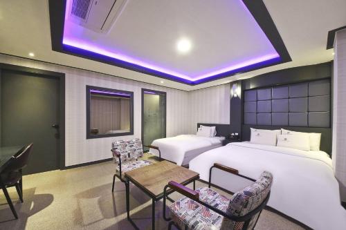 um quarto de hotel com duas camas e uma mesa e cadeiras em Carlton Hotel em Incheon