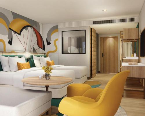 een woonkamer met een witte bank en gele stoelen bij M Social Hotel Phuket in Patong Beach