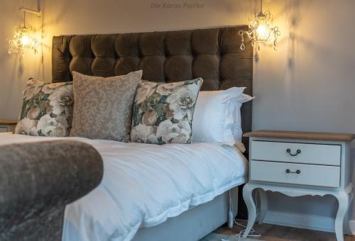 a bed with white sheets and pillows next to a night stand at Die Karoo Patriot in Orania