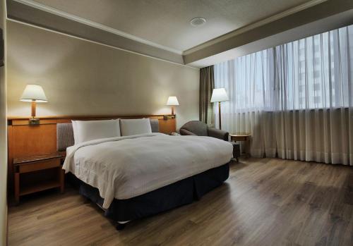 a hotel room with a bed and a large window at The Carlton Hotel Hsinchu in Hsinchu City
