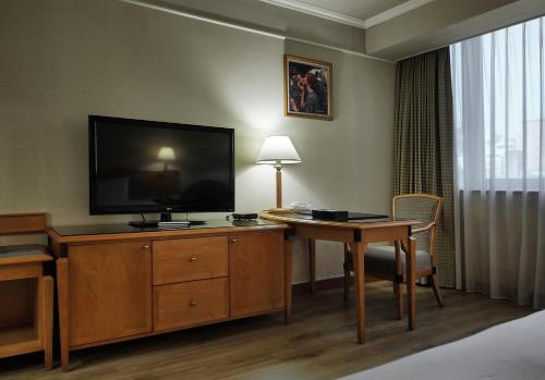 a hotel room with a television and a desk with a table at The Carlton Hotel Hsinchu in Hsinchu City