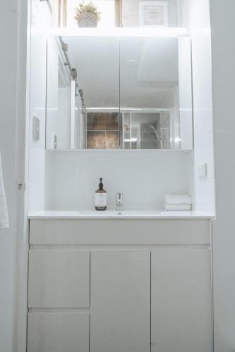 a white bathroom with a sink and a mirror at Cosy studio with a big view in Sydney