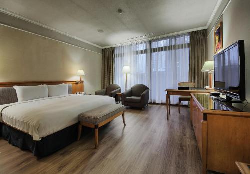 a hotel room with a bed and a flat screen tv at The Carlton Hotel Hsinchu in Hsinchu City