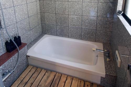 a bath tub in a bathroom with a wooden floor at Hakuba Forest House in Hakuba