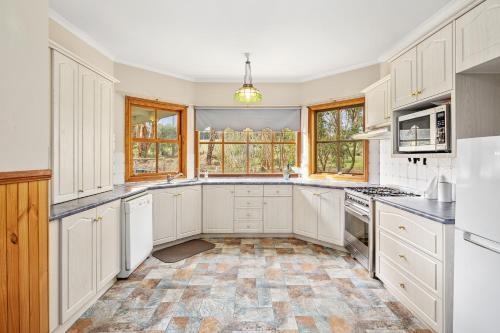 a kitchen with white cabinets and appliances and windows at Perfect Getaway in Phillip Island in Ventnor