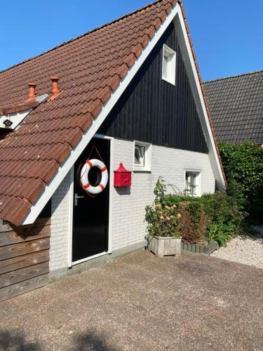 a black and white house with a life preserver on the door at De Lauwersmeer Vogel mit eingezäuntem Garten in Anjum