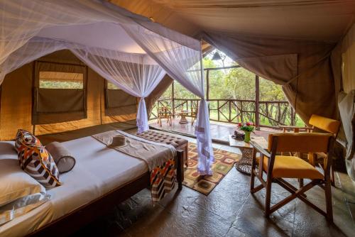 a bedroom in a tent with a bed and a chair at Sentrim Mara Lodge in Ololaimutiek