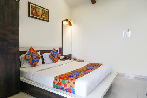 ein Schlafzimmer mit einem großen weißen Bett mit bunten Kissen in der Unterkunft FabHotel Prime Meera Vatika in Mahabaleshwar